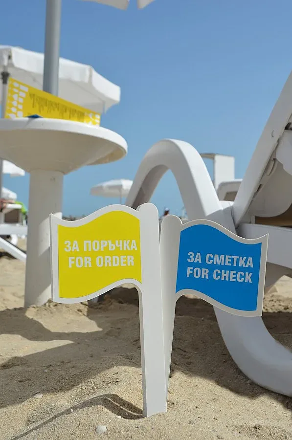 Глезят туристи със сервиз под чадъра на плажа